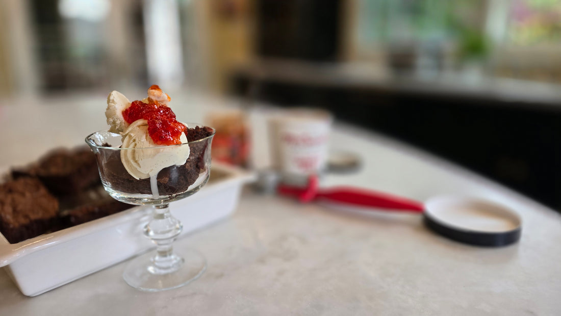 Ice cream and jam on a brownie in a sundae glass.